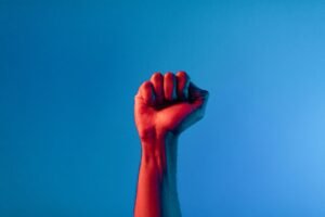 A raised fist against a blue backdrop symbolizing unity and empowerment in a minimalist style.